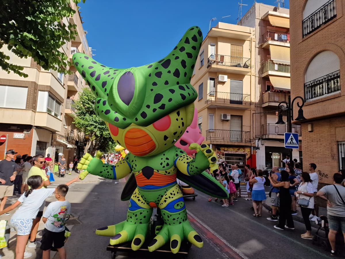 Figura hinchable gigante de personaje verde de gran formato ante familias durante el día