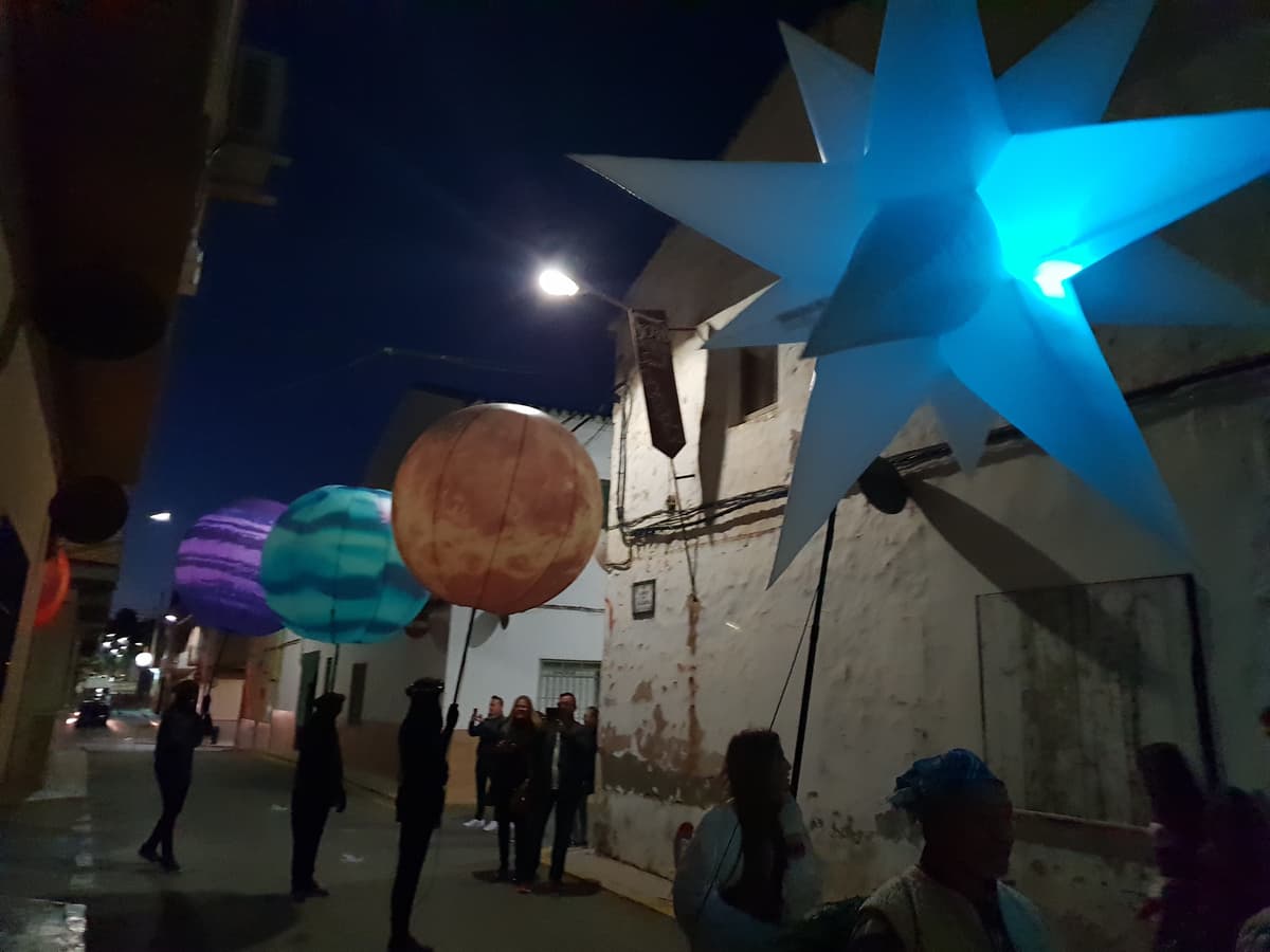 Planetas luminosos y estrella azul avanzando junto al público en las aceras